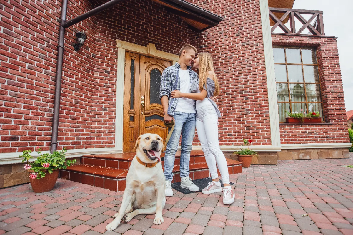 Junges Paar mit Hund vor seinem neuen Klinkerhaus – Haus kaufen im Brookmerland
