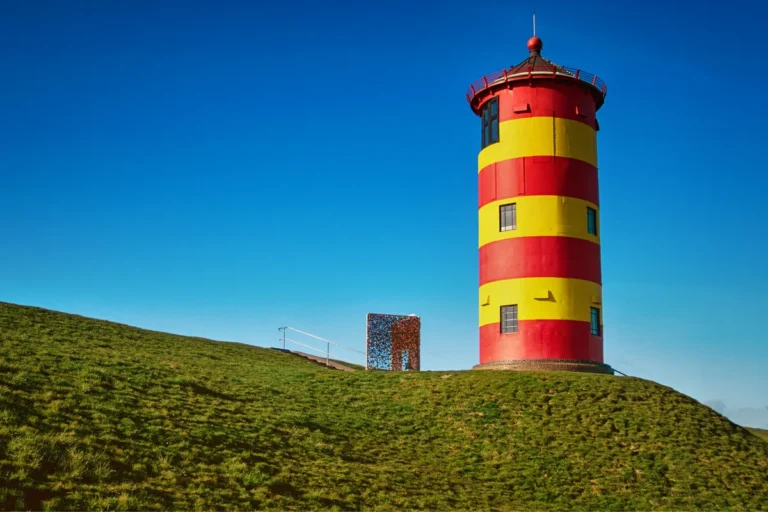Rot-gelb gestreifter Leuchtturm von Pilsum auf dem Deich in der Krummhörn