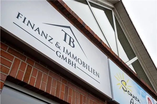 Firmenschild von TB Finanz & Immobilien an der Klinkerfassade des Büros in Upgant-Schott